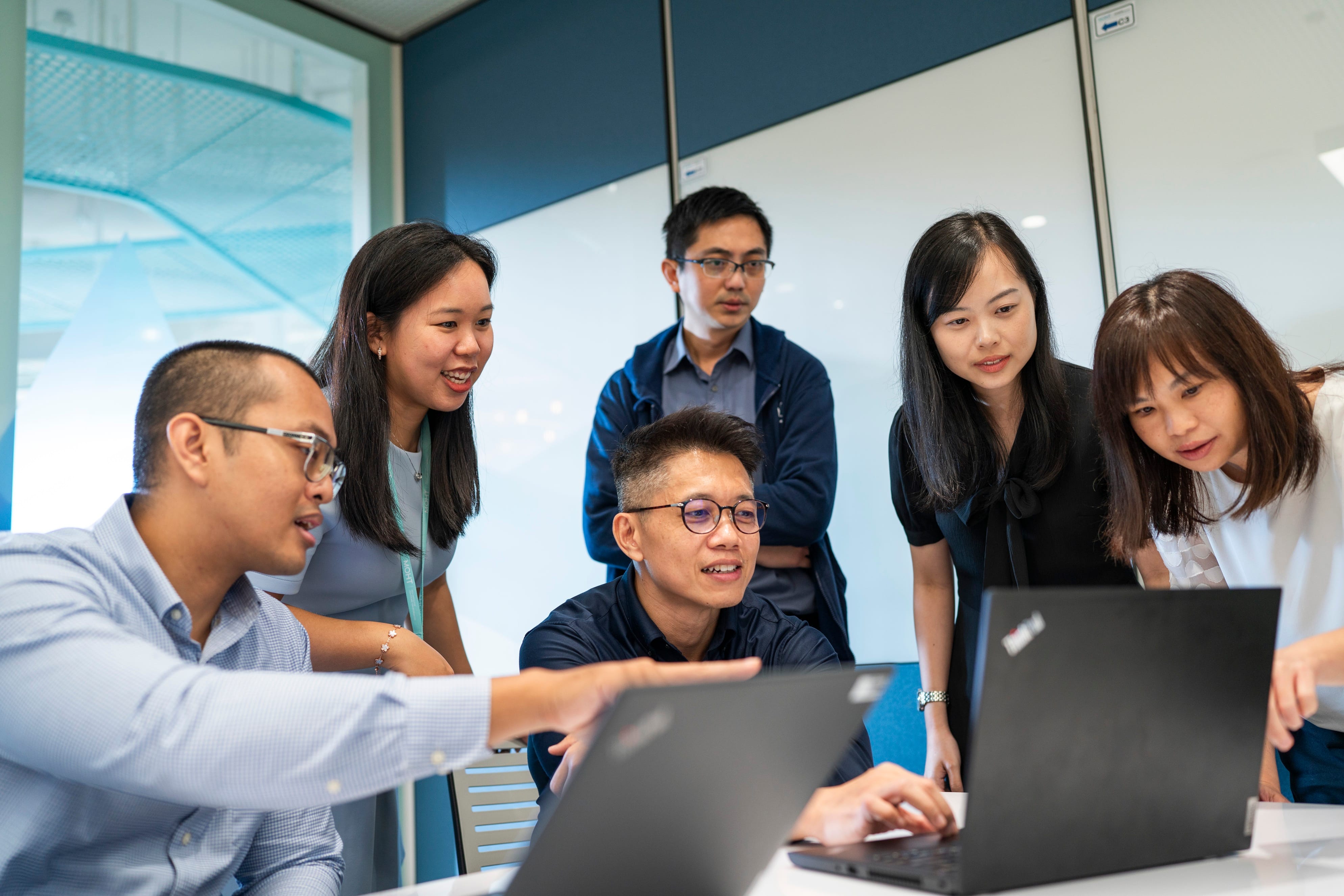 Group of people sitting around a table with magazines and stationery, engaged in a discussion in a professional setting